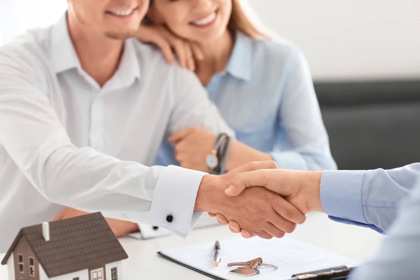 Man and woman together shaking hands with an estate agent